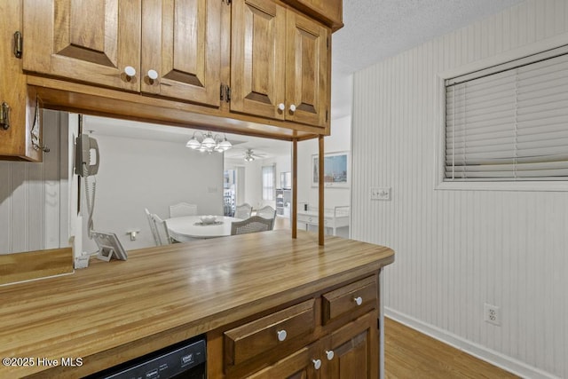 kitchen with butcher block countertops, light wood-style floors, baseboards, brown cabinets, and a ceiling fan