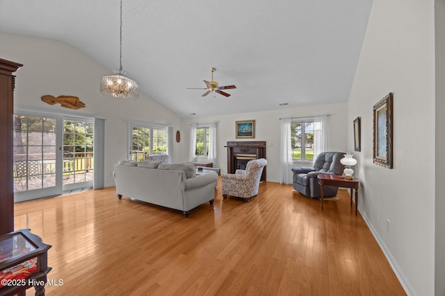 9333 Doris Dr, Oriental, NC 28571 - living room with vaulted ceiling, light wood finished floors, ceiling fan, a glass covered fireplace, and a chandelier