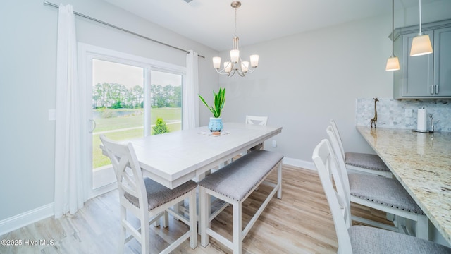 dining space featuring a chandelier, light wood-style floors, and baseboards