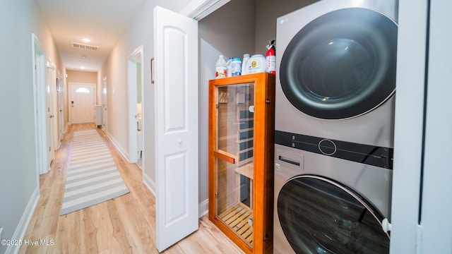 clothes washing area with stacked washer / drying machine, light wood-style flooring, baseboards, and recessed lighting