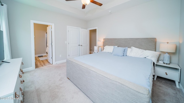 carpeted bedroom featuring baseboards, ensuite bathroom, and ceiling fan