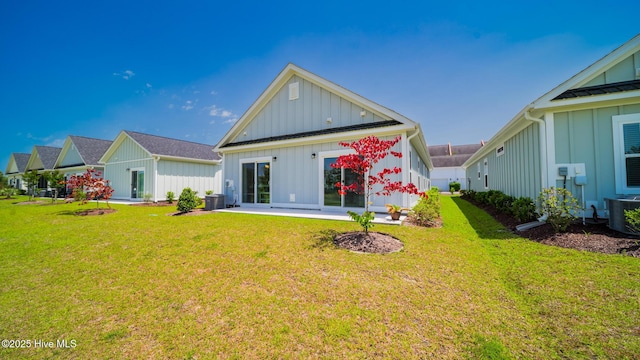 rear view of property with board and batten siding, central AC unit, and a lawn