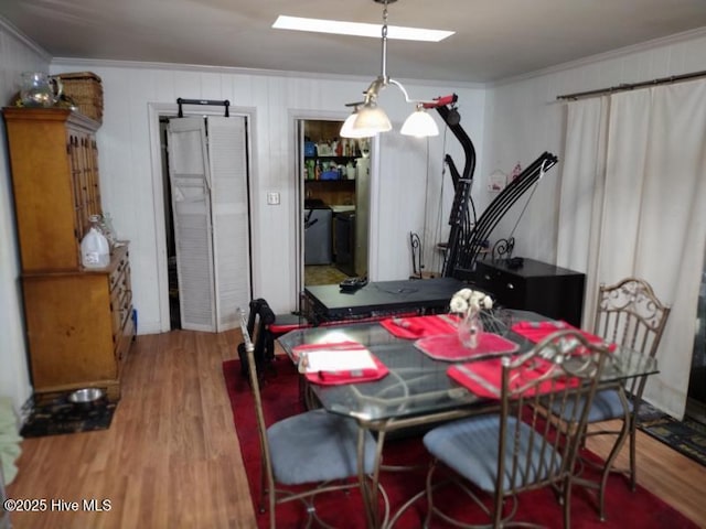 dining space with a skylight, crown molding, and wood finished floors