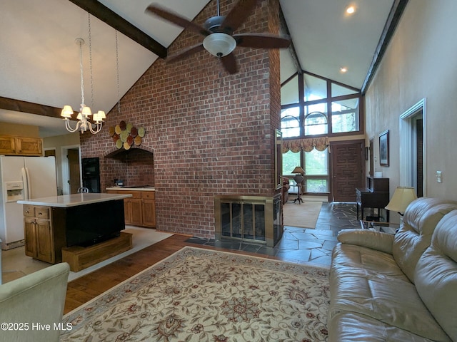 living area featuring high vaulted ceiling, beamed ceiling, a ceiling fan, a chandelier, and a fireplace with flush hearth