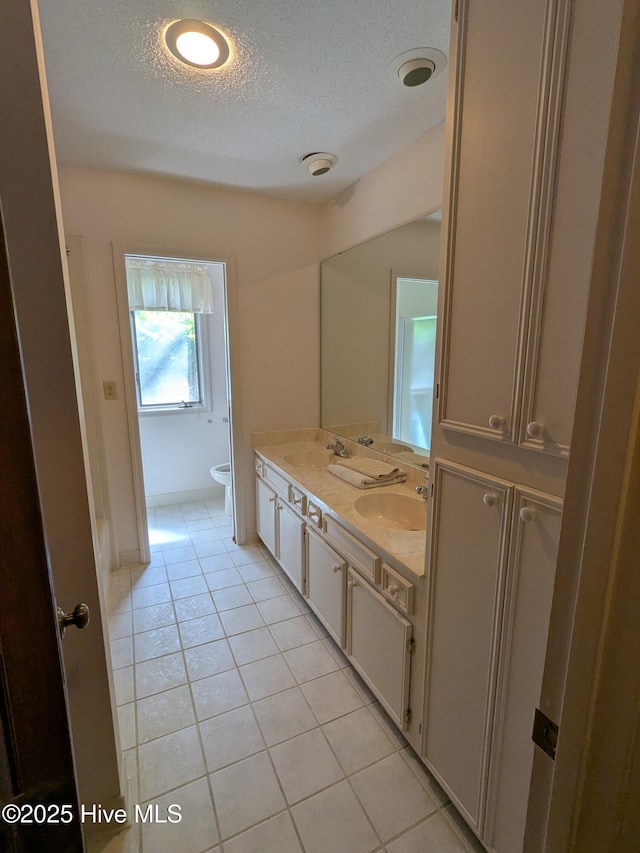 bathroom featuring a textured ceiling, tile patterned flooring, double vanity, and toilet