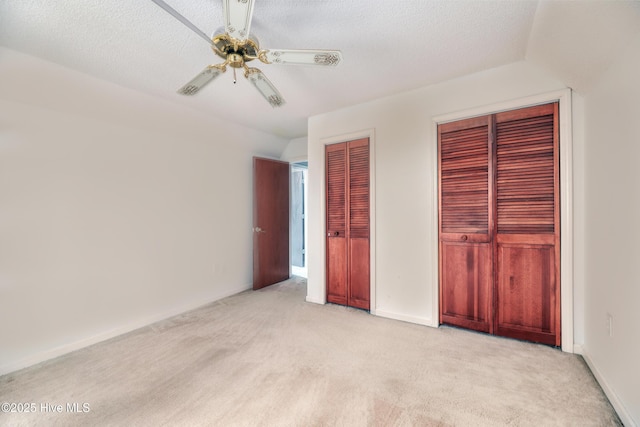 107 Live Oak Ct, Pine Knoll Shores, NC 28512 - unfurnished bedroom featuring multiple closets, light carpet, ceiling fan, baseboards, and a textured ceiling