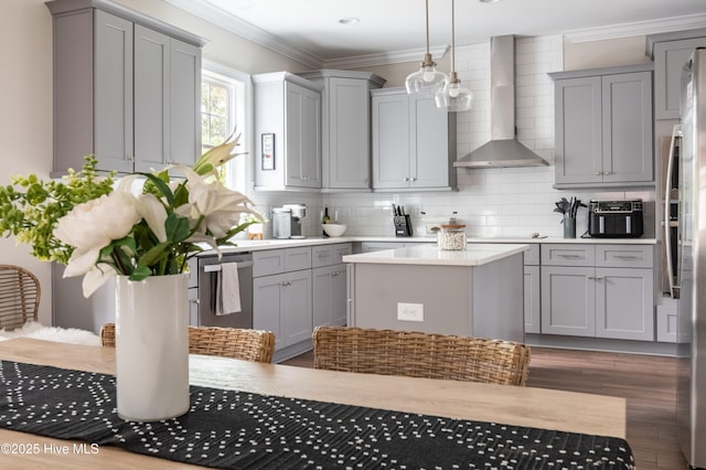 kitchen with gray cabinetry, wall chimney exhaust hood, light countertops, decorative backsplash, and wood finished floors