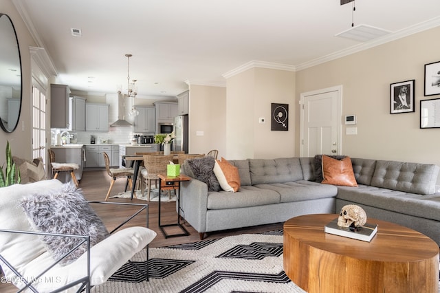 living area with dark wood-style flooring, ornamental molding, and a chandelier