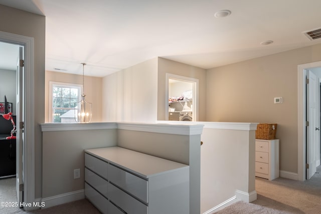 hall with an upstairs landing, light carpet, baseboards, a chandelier, and washer / dryer