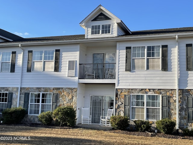 multi unit property featuring stone siding and a balcony