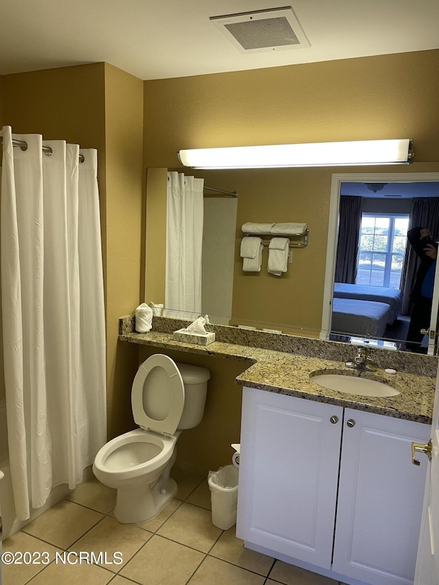 ensuite bathroom featuring tile patterned flooring, toilet, vanity, and a shower with curtain