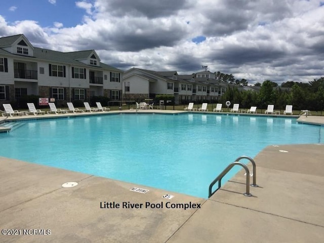community pool featuring fence and a residential view