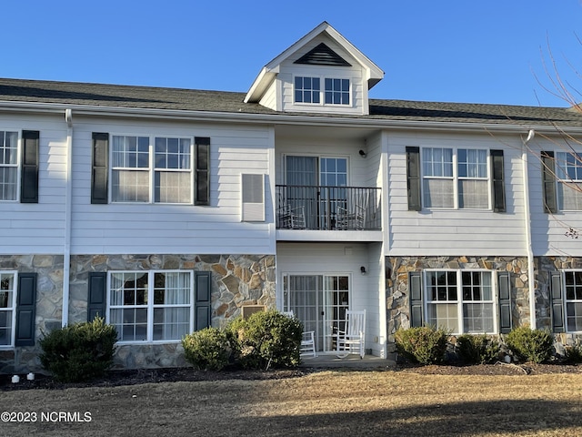 townhome / multi-family property with stone siding and a balcony