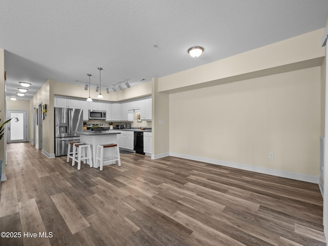 kitchen featuring appliances with stainless steel finishes, white cabinetry, dark wood-style flooring, baseboards, and a textured ceiling