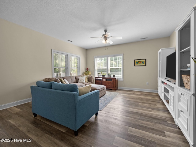 living area featuring a ceiling fan, dark wood-style floors, a textured ceiling, and baseboards
