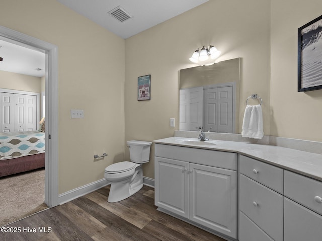 ensuite bathroom featuring wood finished floors, toilet, vanity, and baseboards