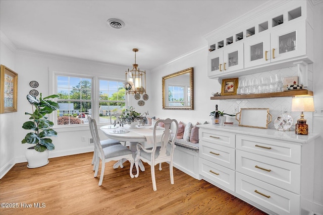125 Windemere Rd, Wilmington, NC 28405 - dining room with light wood-type flooring, ornamental molding, a chandelier, and a dry bar