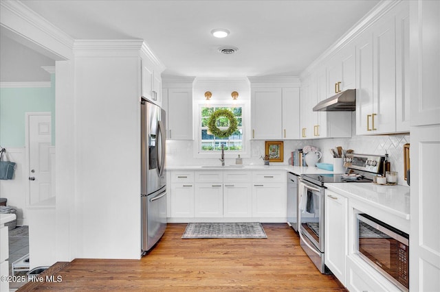 125 Windemere Rd, Wilmington, NC 28405 - kitchen with stainless steel appliances, under cabinet range hood, white cabinetry, light countertops, and crown molding