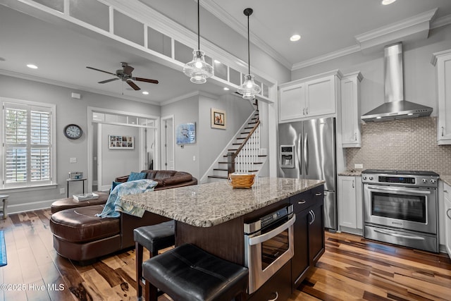 1218 Pinfish Ln, Carolina Beach, NC 28428 - kitchen with wall chimney range hood, appliances with stainless steel finishes, open floor plan, light stone counters, and hardwood / wood-style flooring
