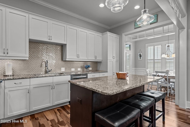1218 Pinfish Ln, Carolina Beach, NC 28428 - kitchen featuring a sink, a breakfast bar, wood finished floors, white cabinetry, and ornamental molding