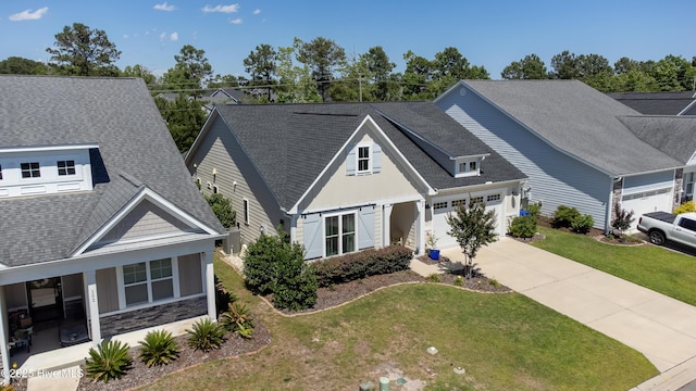 90 N Lamplighters Walk, Hampstead, NC 28443 - view of front of house featuring a garage, driveway, a shingled roof, board and batten siding, and a front lawn