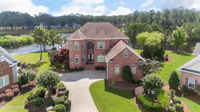 6575 Longwater Ct SW, Ocean Isle Beach, NC 28469 - view of front facade featuring brick siding, concrete driveway, a water view, and a front lawn