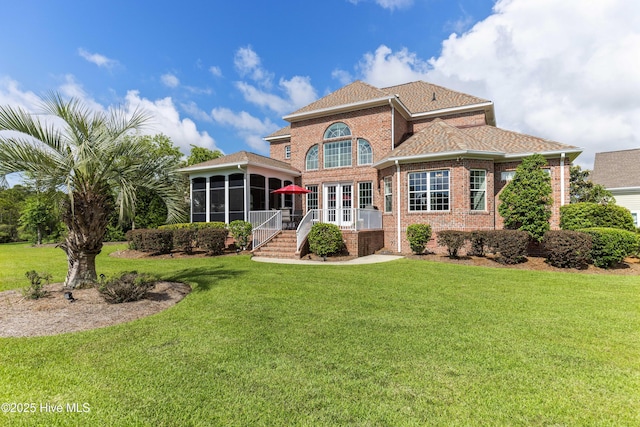 6575 Longwater Ct SW, Ocean Isle Beach, NC 28469 - back of property with a sunroom, brick siding, a yard, and french doors