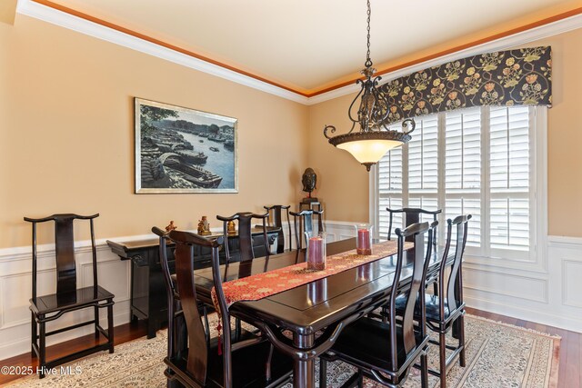 6575 Longwater Ct SW, Ocean Isle Beach, NC 28469 - dining space with wainscoting, wood finished floors, a decorative wall, and crown molding