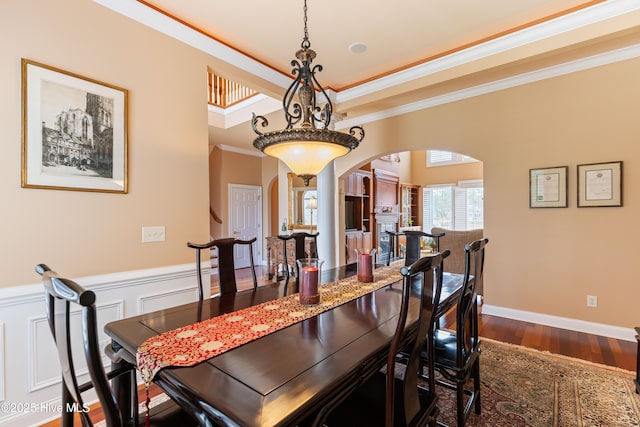 6575 Longwater Ct SW, Ocean Isle Beach, NC 28469 - dining area featuring arched walkways, a wainscoted wall, dark wood finished floors, and crown molding