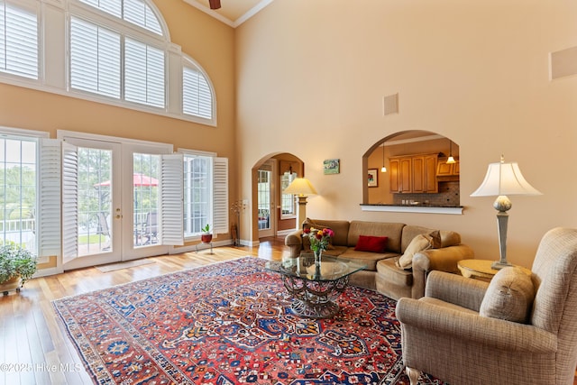 6575 Longwater Ct SW, Ocean Isle Beach, NC 28469 - living area with arched walkways, a high ceiling, french doors, light wood-style flooring, and crown molding