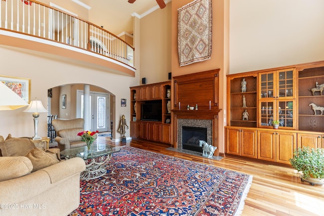 6575 Longwater Ct SW, Ocean Isle Beach, NC 28469 - living area featuring arched walkways, light wood finished floors, a towering ceiling, a high end fireplace, and a ceiling fan