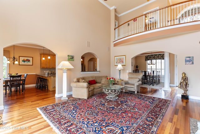 6575 Longwater Ct SW, Ocean Isle Beach, NC 28469 - living area with ornamental molding, arched walkways, wood finished floors, a chandelier, and a towering ceiling
