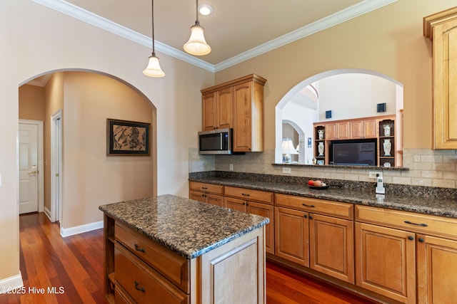 6575 Longwater Ct SW, Ocean Isle Beach, NC 28469 - kitchen featuring stainless steel microwave, decorative backsplash, crown molding, dark wood finished floors, and a center island
