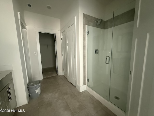 bathroom with a shower stall, toilet, vanity, and a spacious closet