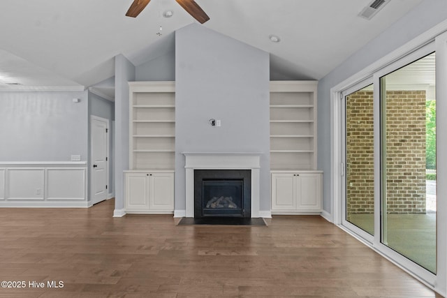 unfurnished living room with vaulted ceiling, ceiling fan, built in features, a fireplace with flush hearth, and wood finished floors