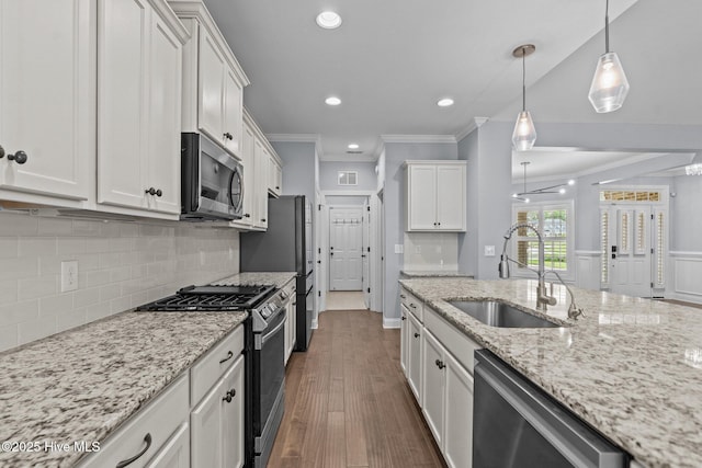 kitchen with appliances with stainless steel finishes, a sink, ornamental molding, white cabinetry, and backsplash