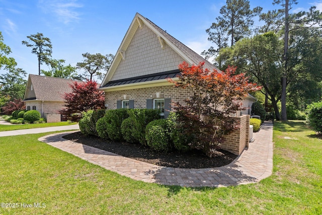 view of property exterior with brick siding, a lawn, and a standing seam roof