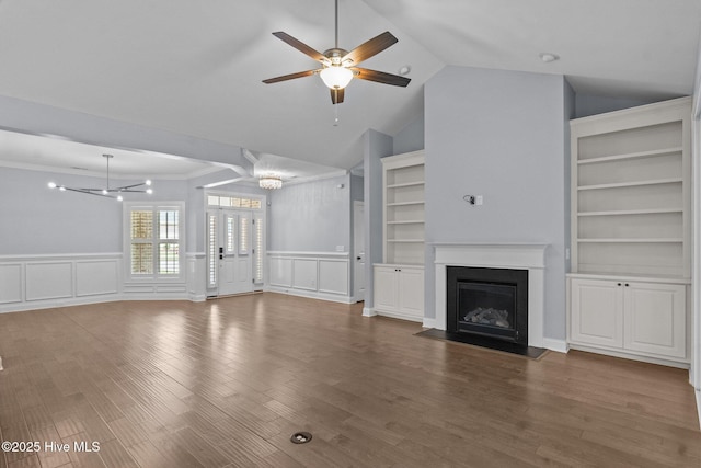 unfurnished living room featuring ceiling fan, a fireplace with flush hearth, a decorative wall, lofted ceiling, and wainscoting