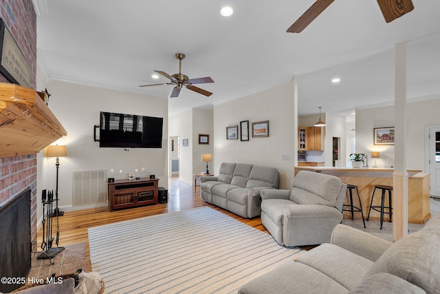 101 Mallard Dr, Currituck, NC 27929 - living area with ceiling fan, crown molding, light wood-style floors, a fireplace, and baseboards