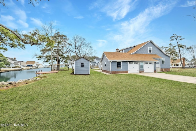 101 Mallard Dr, Currituck, NC 27929 - view of green lawn with a shed, a water view, concrete driveway, a garage, and an outdoor structure