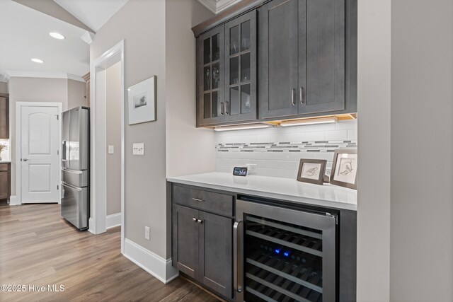 3032 Beachcomber Dr, Southport, NC 28461 - indoor dry bar with wine cooler, stainless steel fridge with ice dispenser, backsplash, crown molding, and baseboards