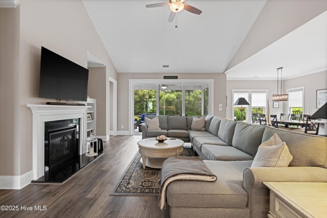 3032 Beachcomber Dr, Southport, NC 28461 - living area featuring a ceiling fan, dark wood-style flooring, a glass covered fireplace, baseboards, and high vaulted ceiling