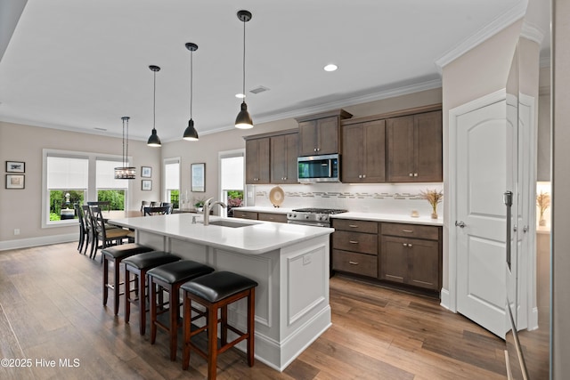 3032 Beachcomber Dr, Southport, NC 28461 - kitchen with stainless steel appliances, a sink, a kitchen bar, light countertops, and a kitchen island with sink