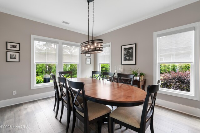 3032 Beachcomber Dr, Southport, NC 28461 - dining space with baseboards, healthy amount of natural light, crown molding, light wood-style flooring, and a chandelier