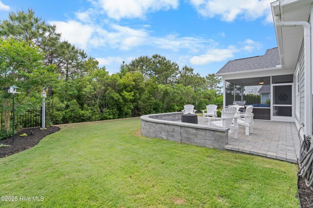 3032 Beachcomber Dr, Southport, NC 28461 - view of grassy yard with a sunroom, a patio area, a ceiling fan, and a fire pit