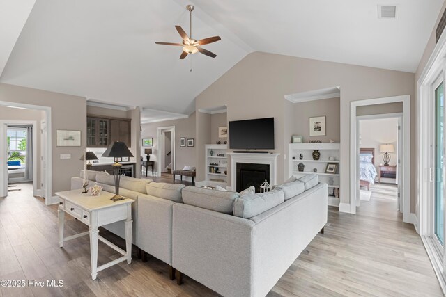 3032 Beachcomber Dr, Southport, NC 28461 - living area featuring a fireplace, a ceiling fan, light wood-style floors, high vaulted ceiling, and baseboards
