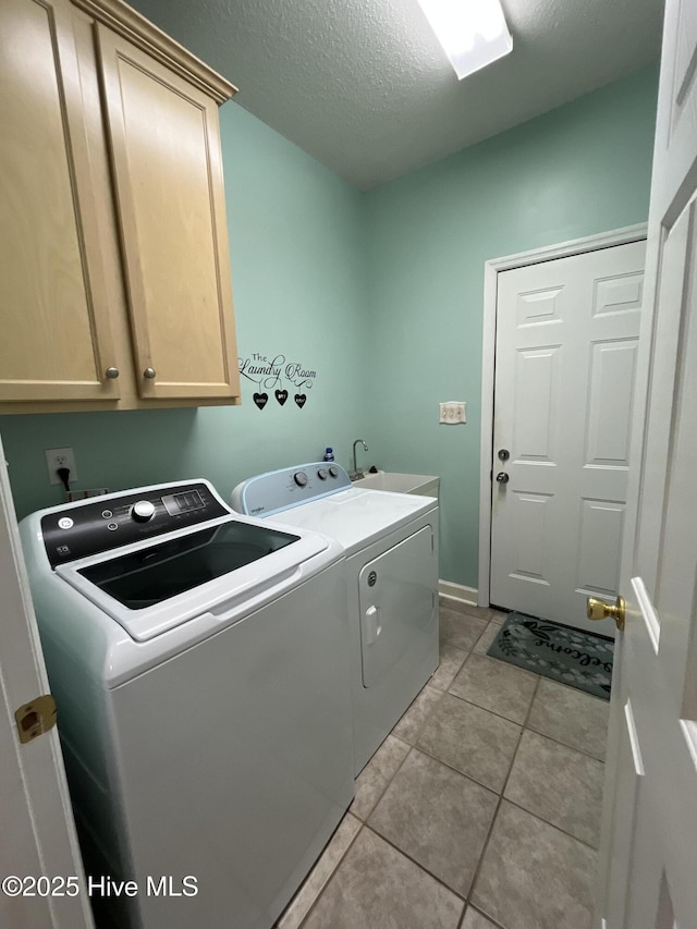 laundry room featuring separate washer and dryer, cabinet space, light tile patterned floors, a textured ceiling, and baseboards