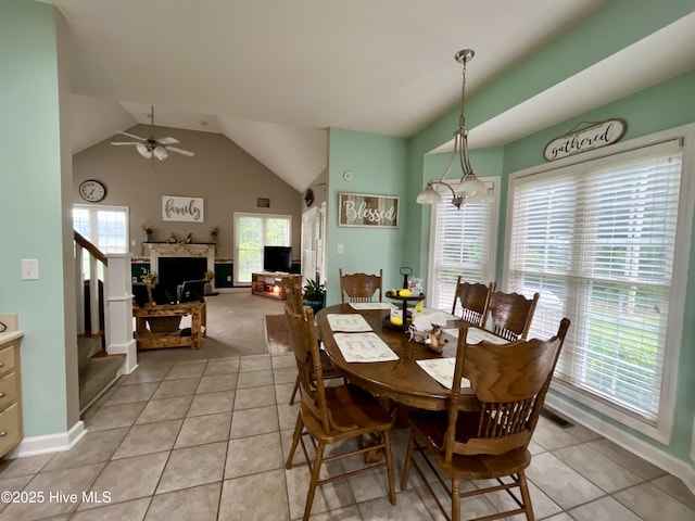 dining area with light tile patterned floors, lofted ceiling, ceiling fan, baseboards, and light carpet