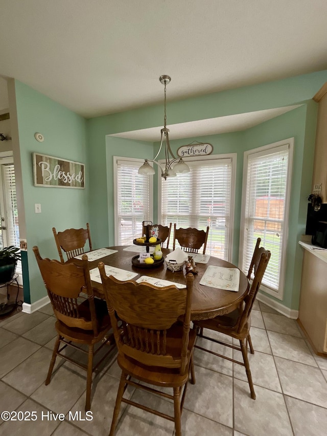 dining space featuring light tile patterned floors, baseboards, and a chandelier