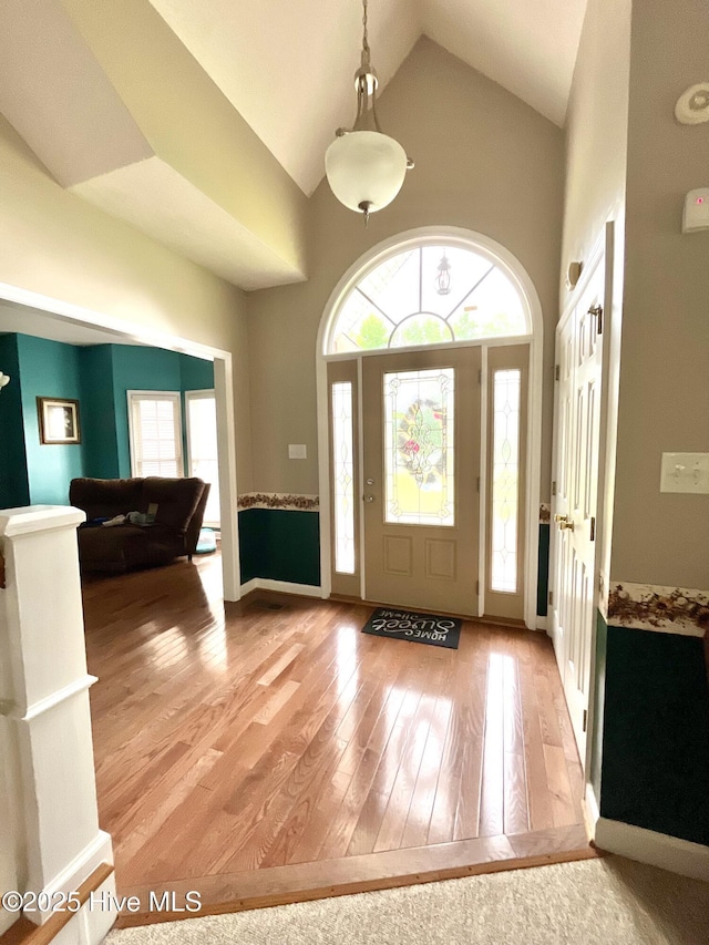 entryway featuring plenty of natural light, light wood finished floors, high vaulted ceiling, and baseboards
